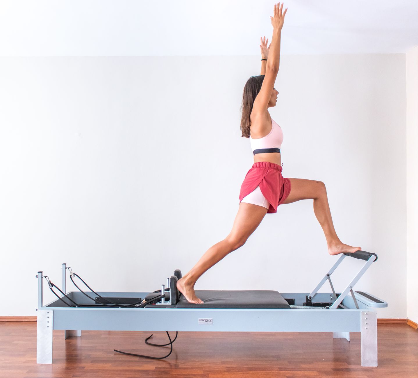 A woman balancing on a pilates reformer